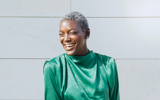 person in a white sweater standing in front of a graffiti wall