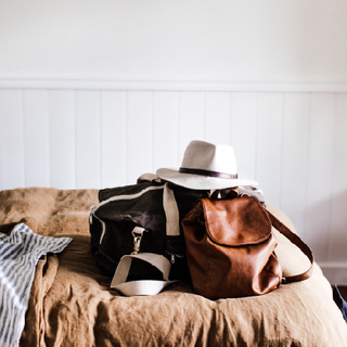 Picture of a hotel room and a guests bag, sunglasses, hat