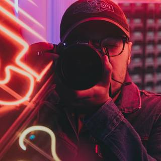 Man lit by neon holding camera