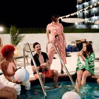 Group of friends around pool at night